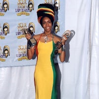 a woman in a colorful dress holding two trophies