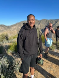 a man in a black hoodie standing on a mountain