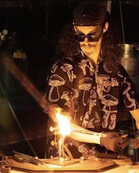 a man with glasses is working on a piece of glass