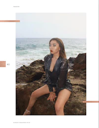 a woman is posing on rocks near the ocean
