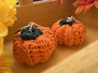 two crocheted pumpkin keychains on a wooden table