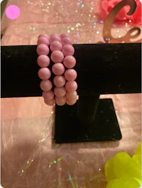 two pink beaded bracelets on a black stand