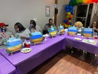 a group of people sitting at a table painting