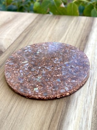 a copper coaster sitting on top of a wooden table