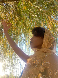 a woman reaching up to a willow tree