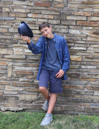 a boy wearing a hat leaning against a brick wall