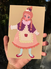 a hand holding a card with an image of a girl in a dress