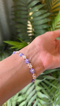 a woman's hand holding a bracelet with purple and white beads