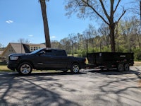 a black ram truck with a trailer parked in front of a house