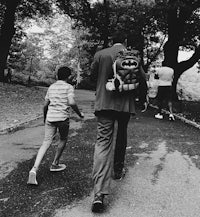 a man and a boy walking down a path with a backpack