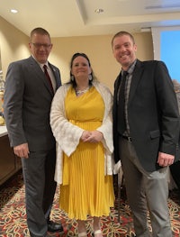 three people standing next to each other in a room