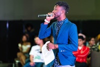 a man in a blue suit is singing into a microphone