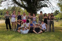 a group of people posing in front of a tree