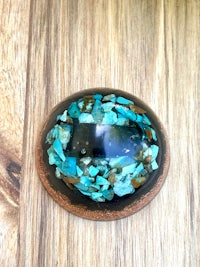 a turquoise and brown stone pendant on a wooden table