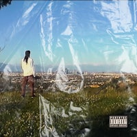 a man standing on a grassy hill with a city in the background