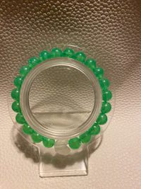 a green beaded bracelet on a white surface