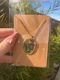 a person holding a necklace with a green moss on it
