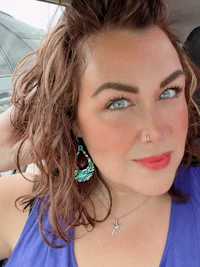 a woman sitting in a car with blue earrings