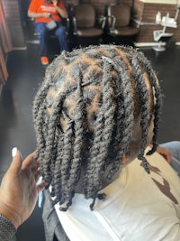 a woman is getting her hair braided in a salon