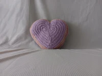 a heart shaped crocheted pillow on a bed