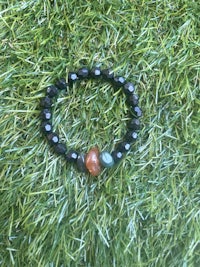 a black and orange stone bracelet on the grass