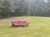 a red couch in the middle of a grassy field
