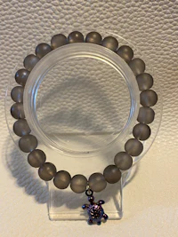 a clear glass holder with a grey bead on it