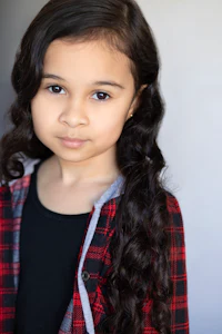 a young girl in a plaid shirt posing for a photo