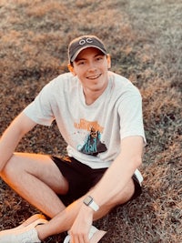 Alex sitting on grass with a cool Olympics t-shirt on.