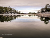 a lake surrounded by trees and a cloudy sky