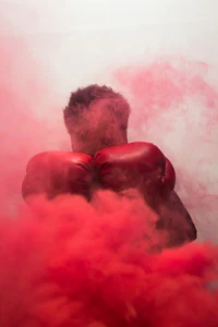 a man in red boxing gloves is covered in red smoke