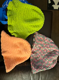 three crocheted hats sitting on a couch