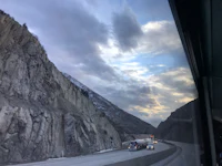 a view from the window of a bus on a highway with mountains in the background