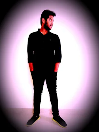 a man in a black shirt standing in front of a pink background
