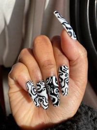 a person holding a black and white nail design