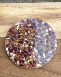 a colorful stone coaster sitting on top of a wooden table