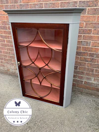 a wooden cabinet with glass doors and a brick wall