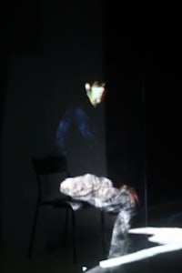 a person sitting on a chair in a dark room