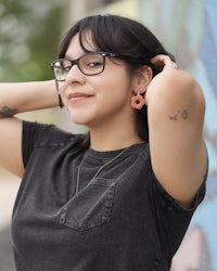 a woman wearing glasses and a t - shirt is posing for a photo