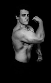 a man flexing his muscles in a black and white photo