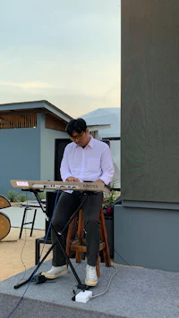 a man playing a keyboard on a stage in front of a building