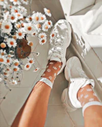 a pair of white sneakers with daisies on them