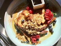 a plate of french toast with berries and granola