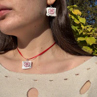 a woman wearing a necklace with a red flower on it