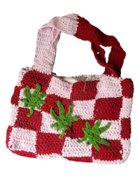 a red and white crocheted bag with green leaves