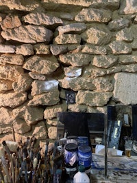 a room with paint brushes and paint on a stone wall