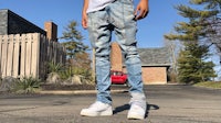 a man is standing in front of a house wearing jeans