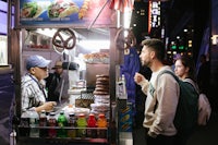 a group of people standing in front of a food cart at night