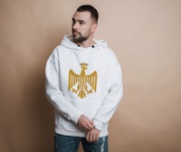 a man wearing a white hoodie with a golden eagle on it