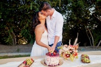 a bride and groom kissing in front of a cake
